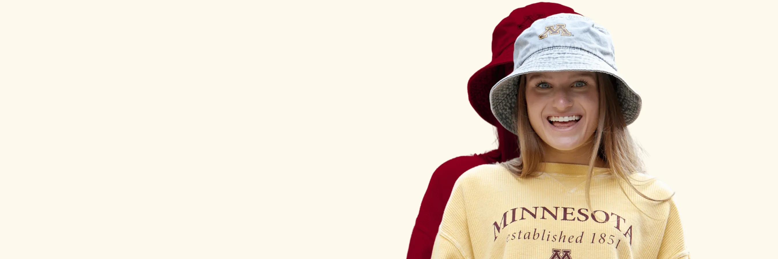 female student wearing UMN bucket hat and crew neck, smiling excitedly.